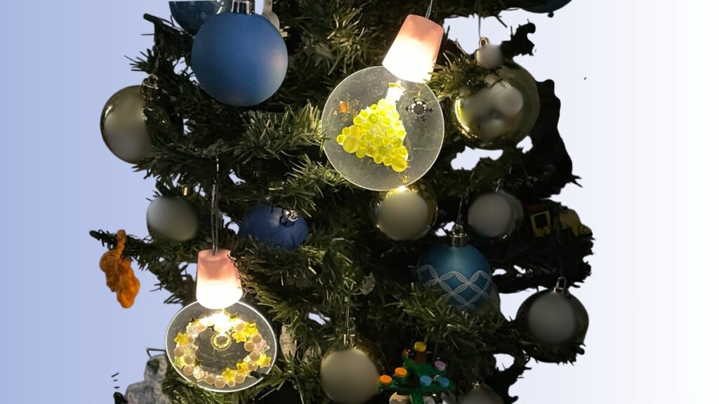 光る手作りオーナメントをツリーに飾る